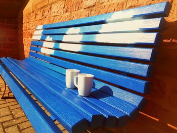 blaue Bank mit aufgemalten Wolken, auf der zwei weiße Tassen stehen